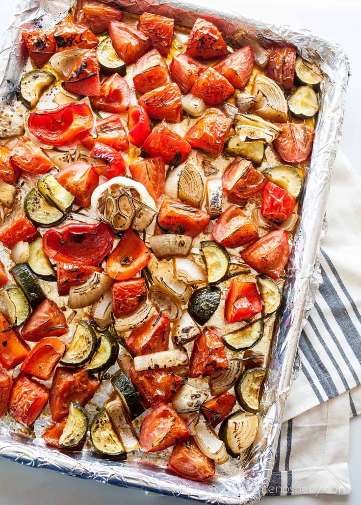 a sheet pan filled with roasted vegetables on top of a table next to a striped towel