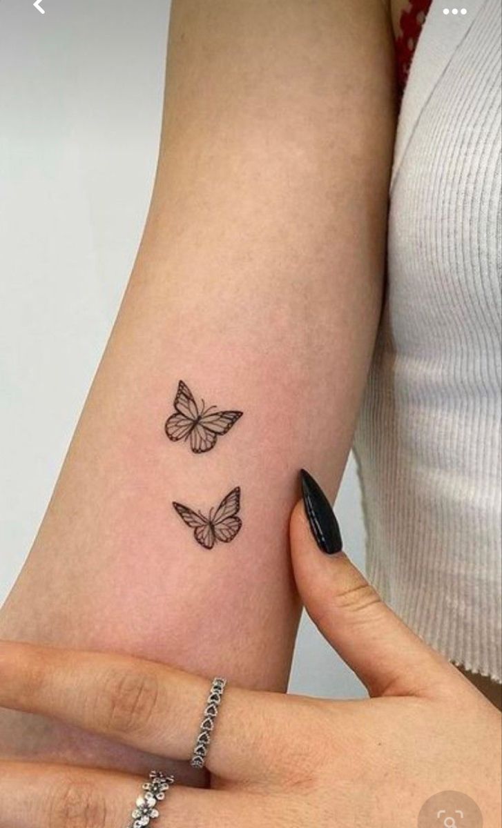 a woman's arm with three butterflies tattooed on the left side of her arm