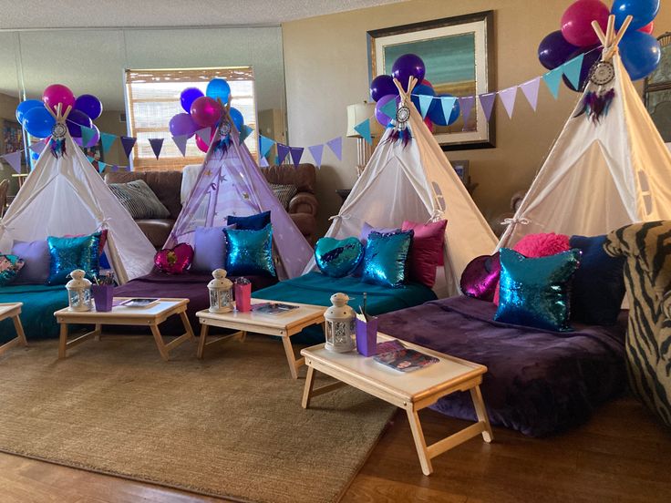 a living room filled with lots of purple and blue furniture next to balloons hanging from the ceiling