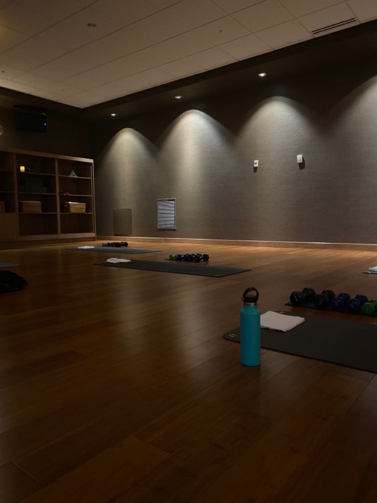 an empty gym room with yoga mats and water bottles