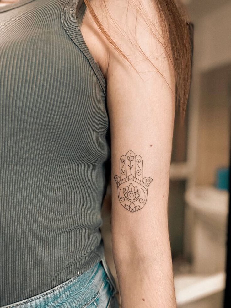 a woman with a small hamsa tattoo on her arm