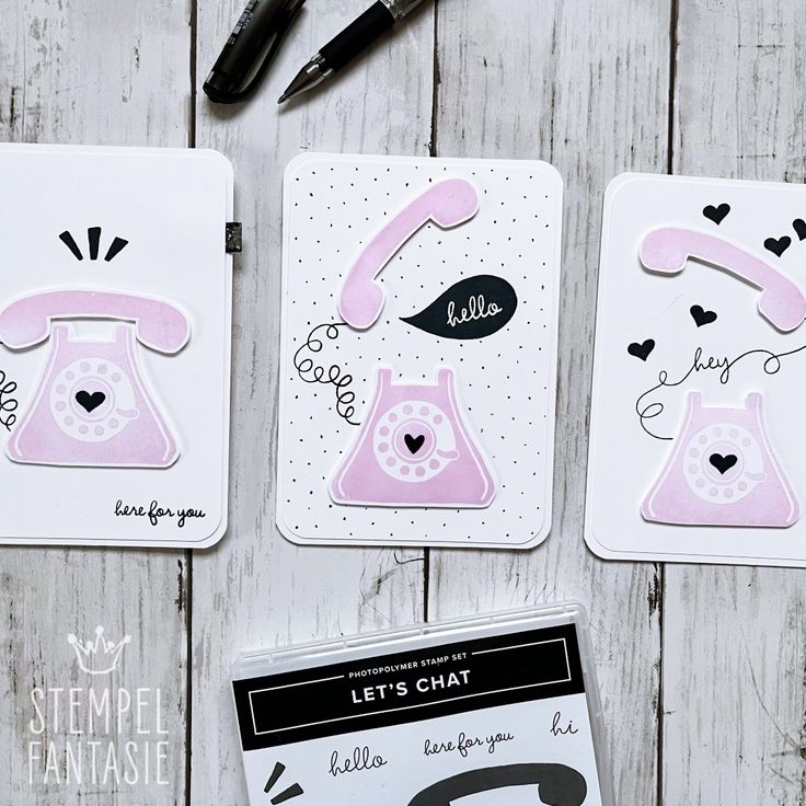 three cards with different designs on them next to a pen and marker, scissors and paper