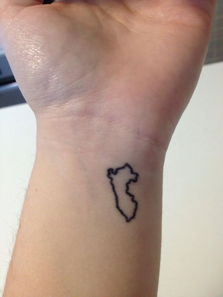 a small tattoo on the wrist of a woman's arm that has a black outline of a map