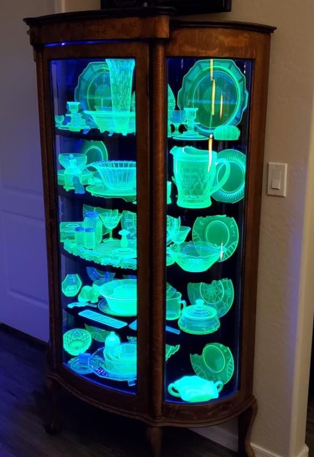 a lighted display case in the corner of a room with plates and cups on it