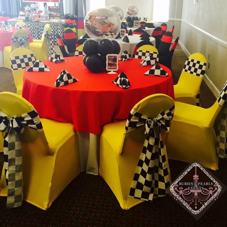 a red table topped with yellow chairs covered in black and white checkered bows