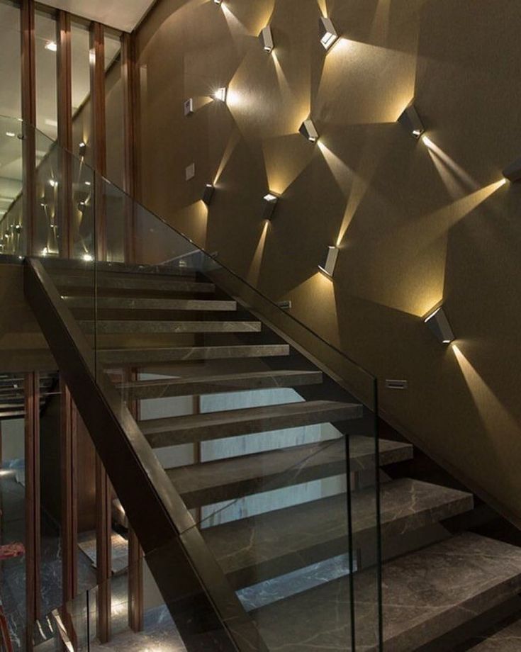 a stair case with glass railings and lights on the wall next to it,