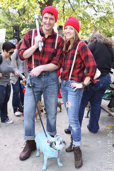 two people standing next to each other with a dog on a leash in front of them