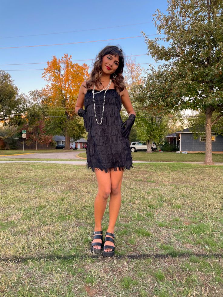 a woman standing in the grass with her hands on her hips and wearing black sandals