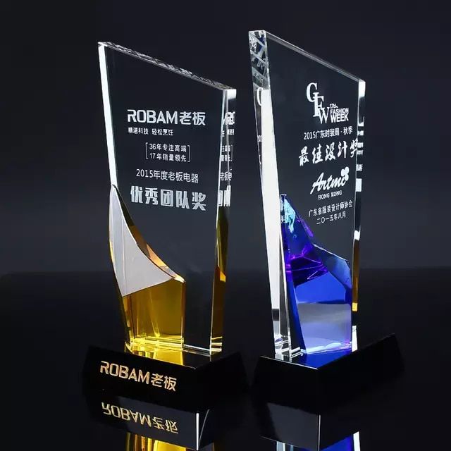 two glass awards are shown on a black surface