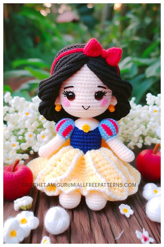 a crocheted doll sitting on top of a wooden table next to white flowers