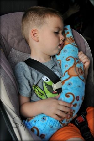 a young boy sleeping in a car seat with a stuffed animal on it's back