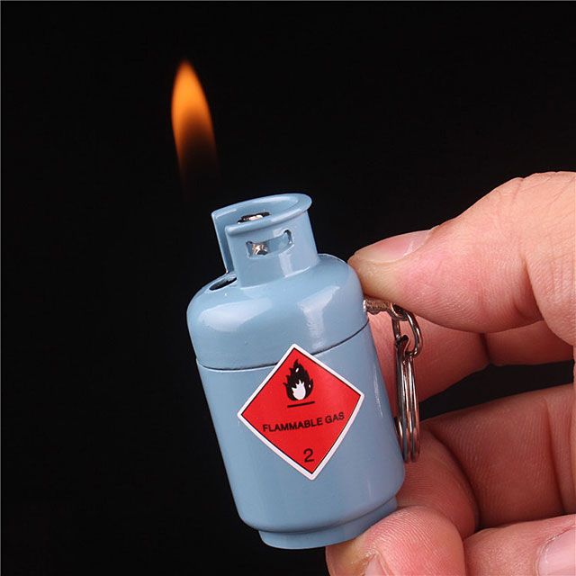 a hand holding a lighter with a flame coming out of it's top end