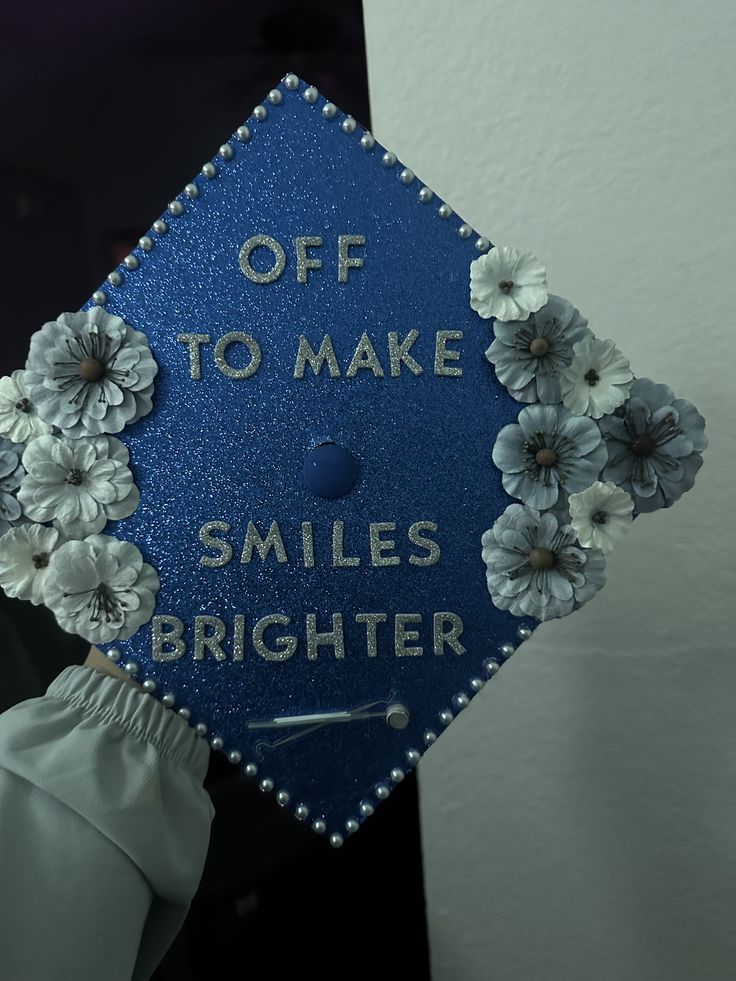 a blue graduation cap with flowers on it that says, off to make smiles brighter