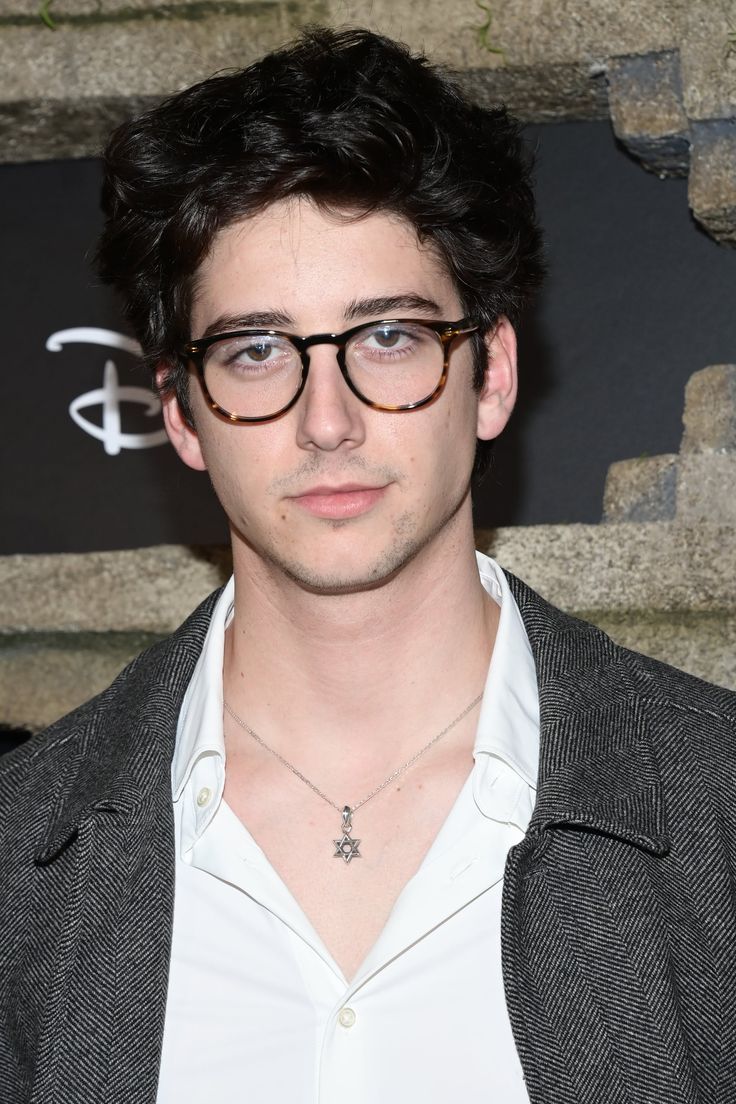 a young man wearing glasses poses for the camera