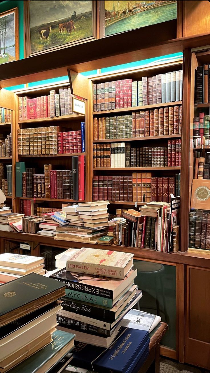 many books are stacked on top of each other in front of a wooden bookcase