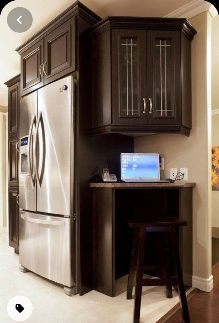 a refrigerator freezer sitting inside of a kitchen next to a counter top with a laptop on it