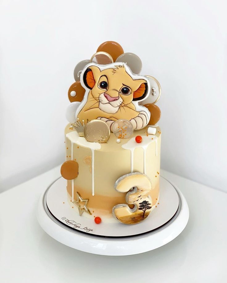 a birthday cake with a lion on top and decorations around the edges, sitting on a white plate