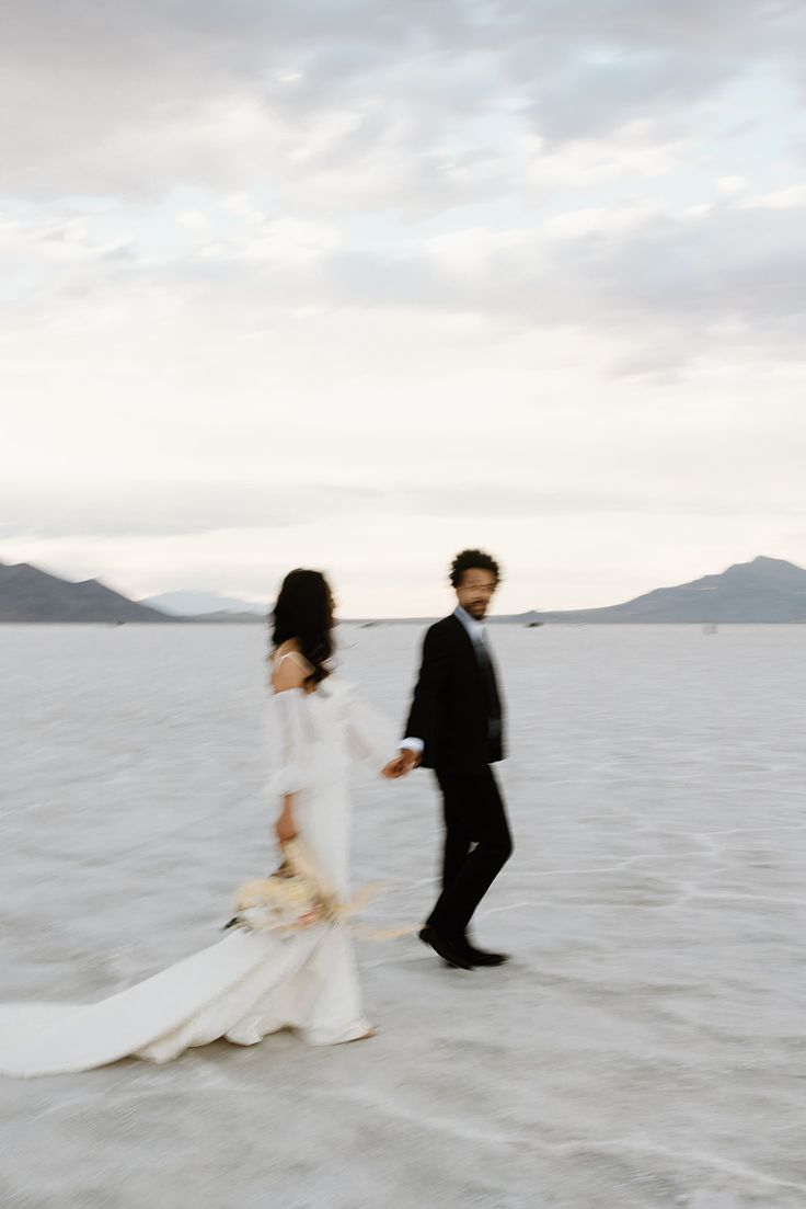 a bride and groom walking across the salt flats