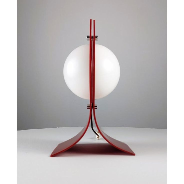 a red and white table lamp on a grey surface with an egg in the middle