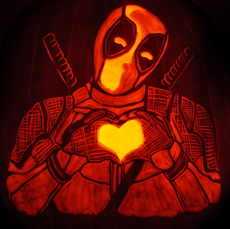 a carved pumpkin with a drawing of a deadpool holding two knives and heart on it