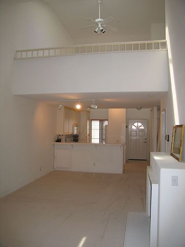 an empty living room with white walls and ceiling fan