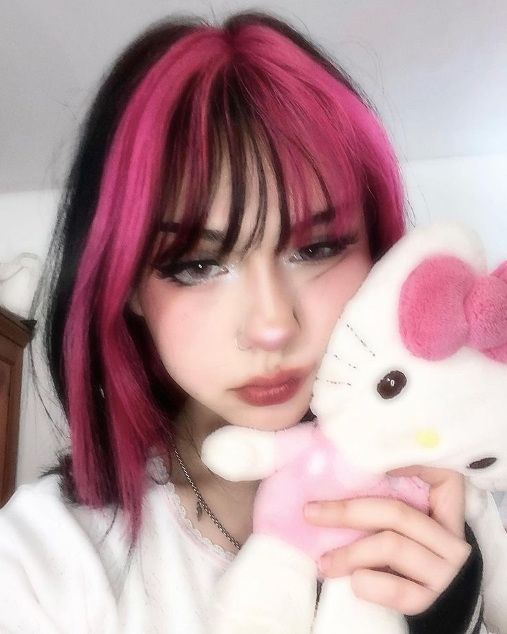 a girl with pink hair holding a hello kitty stuffed animal