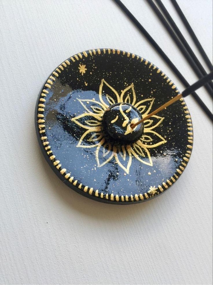 a black and gold plate with a sunflower on it next to some chopsticks