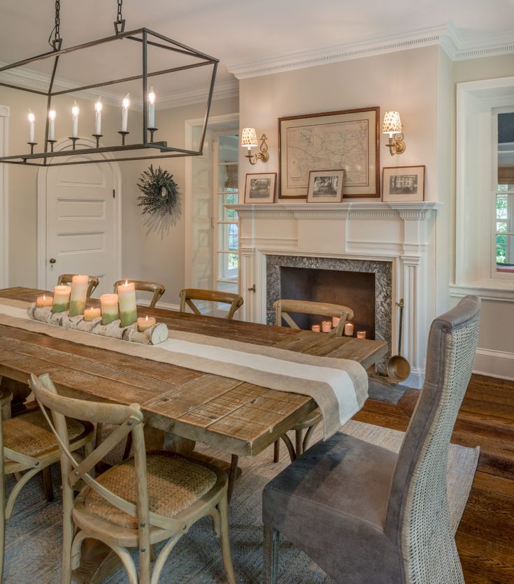 a dining room table with candles on it in front of a fire place and chandelier