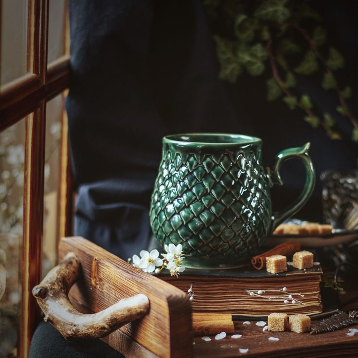 a green coffee mug sitting on top of a wooden tray next to some crackers