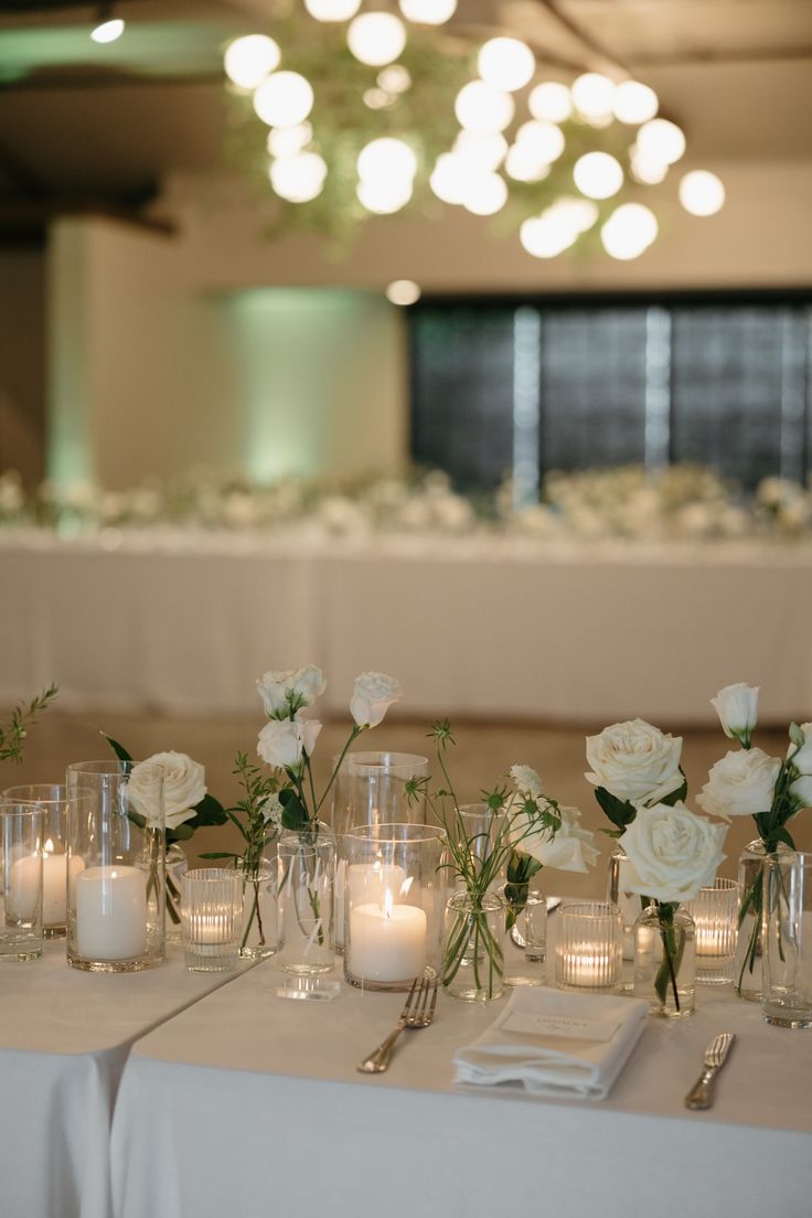 the table is set with white flowers and candles for an elegant wedding breakfast or reception