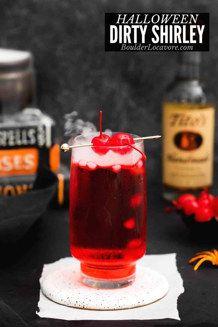 a red drink sitting on top of a white napkin next to halloween decorations and bottles