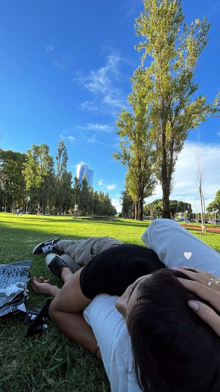 two people laying on the grass with their backs to each other