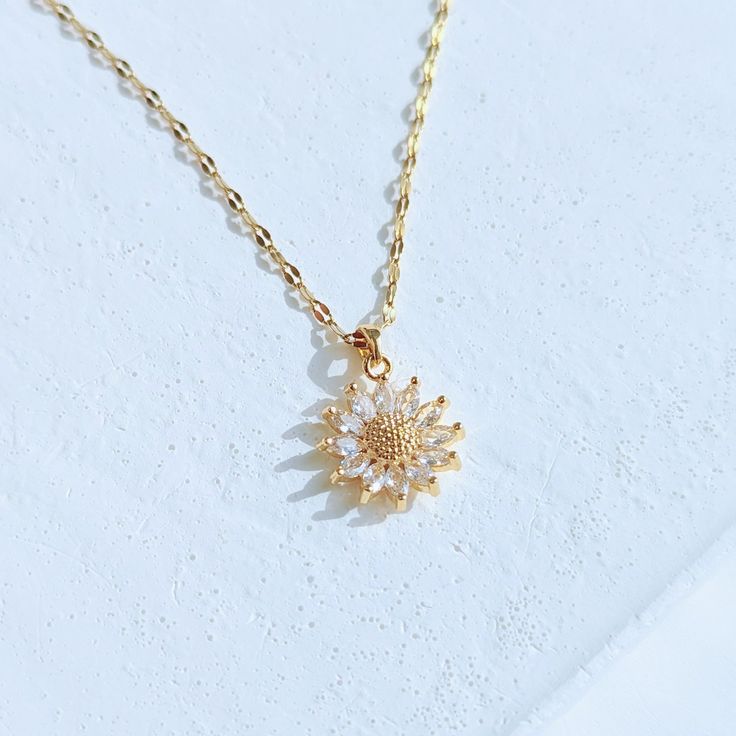 Our genuine, high-quality Sunflower Necklace is a unique statement piece that will make any outfit look more elegant. This elegant floral necklace is made of real stainless steel dipped in 18k gold and accented with cubic zirconia crystals. It’s hypoallergenic, water resistant and handcrafted in California. ✔Hypoallergenic ✔Quality Guaranteed ✔Water Resistant ✔Handmade MATERIAL: stainless steel dipped in real 18k gold COLOR: gold, cubic zirconia crystals LENGTH: 18 inches Gold Flower-shaped Cubic Zirconia Necklaces, Gold Flower Necklace With Cubic Zirconia, Gold Flower-shaped Necklace With Cubic Zirconia, White Cubic Zirconia Flower Necklace, White Cubic Zirconia Necklaces With Flower Shape, White Cubic Zirconia Flower-shaped Necklaces, White Cubic Zirconia Necklace In Flower Shape, White Cubic Zirconia Floral Necklace, Sunflower Necklace