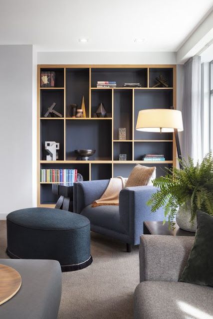 a living room filled with lots of furniture and bookshelves next to a window