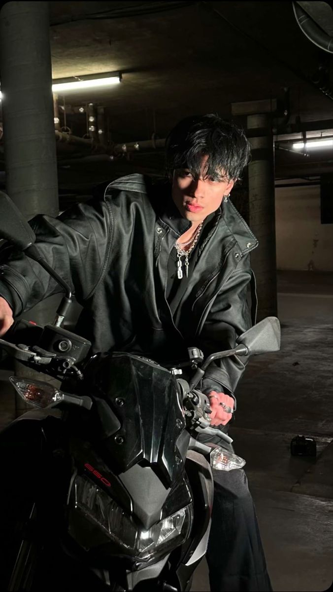 a man sitting on top of a motorcycle in a parking garage with his hand on the handlebars