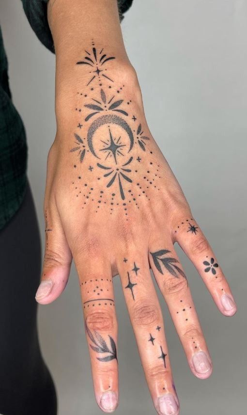 a woman's hand with tattoos on it and stars in the middle of her fingers