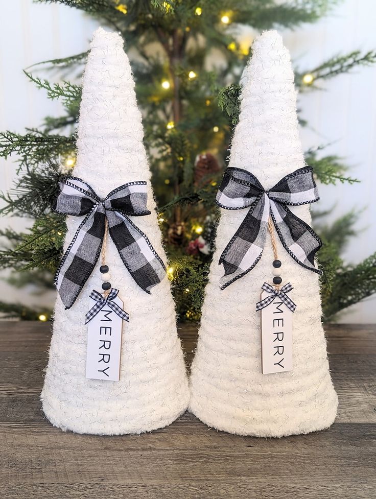 two white christmas trees with black and white bows on them, one has a tag that says merry