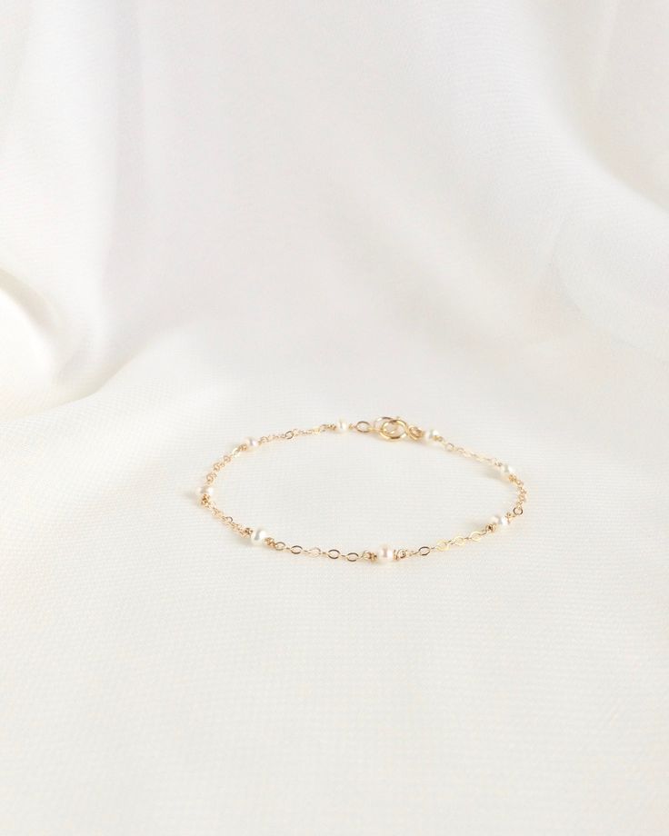 Classic and feminine, this dainty pearl bracelet can be worn for everyday effortless style. Beautiful tiny pearls are wire wrapped by hand throughout this delicate chain bracelet. Its simple and sophisticated design can be worn alone or layered with your favorite pieces for a touch of elegance. Available in 14k Gold Filled or Sterling Silver. Details: Dainty Minimalist Pearl Chain Bracelet Tiny 2mm - 3mm Cream Freshwater Pearls Thin Delicate 2mm Cable Chain Spring Ring Clasp Closure Choose Your Dainty Pearl Bracelet, Minimal Choker, Bell Bracelet, Delicate Stacking Rings, Dainty Gold Bracelet, Bracelet Simple, Bracelet Dainty, Dainty Bracelet, Delicate Chain