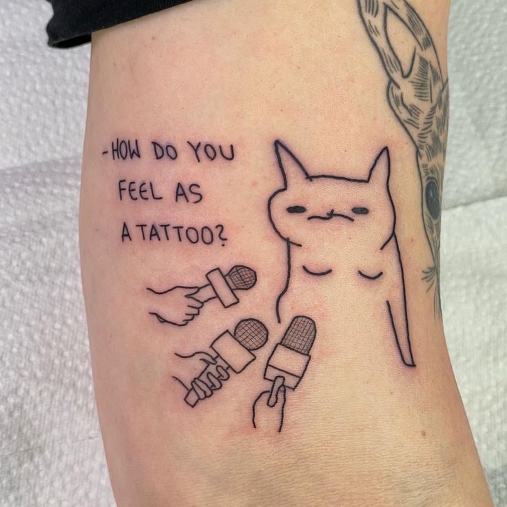 a tattoo with an image of a cat and a microphone on the side of her leg