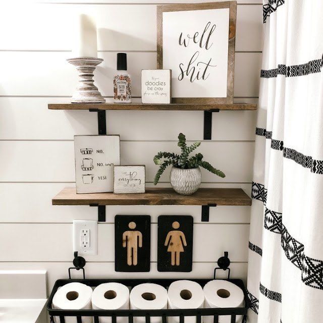 the bathroom is decorated in black and white, with wood shelves above the toilet paper dispenser