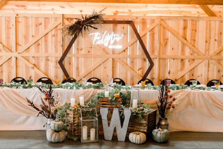 the table is set up with candles, greenery and pumpkins for an autumn wedding