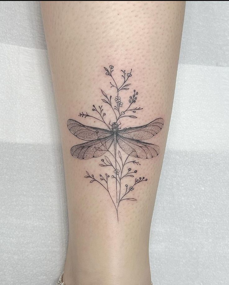 a woman's leg with a dragonfly tattoo on it