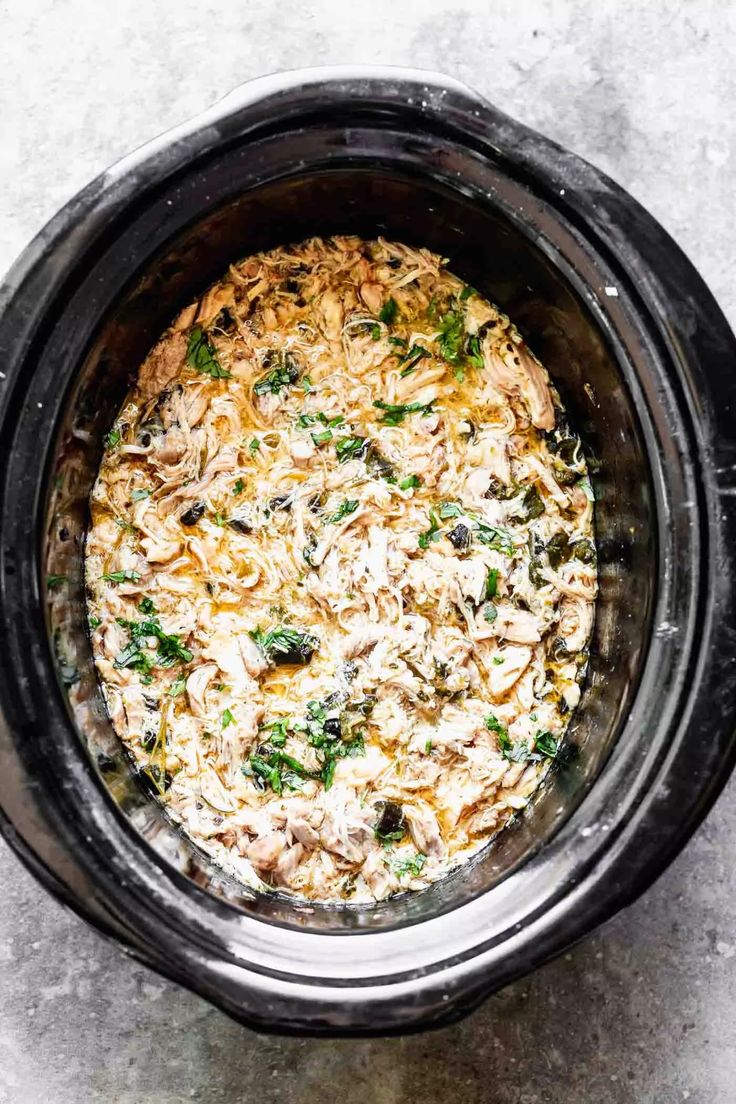 an overhead view of a crock pot filled with shredded cheese and vegetables