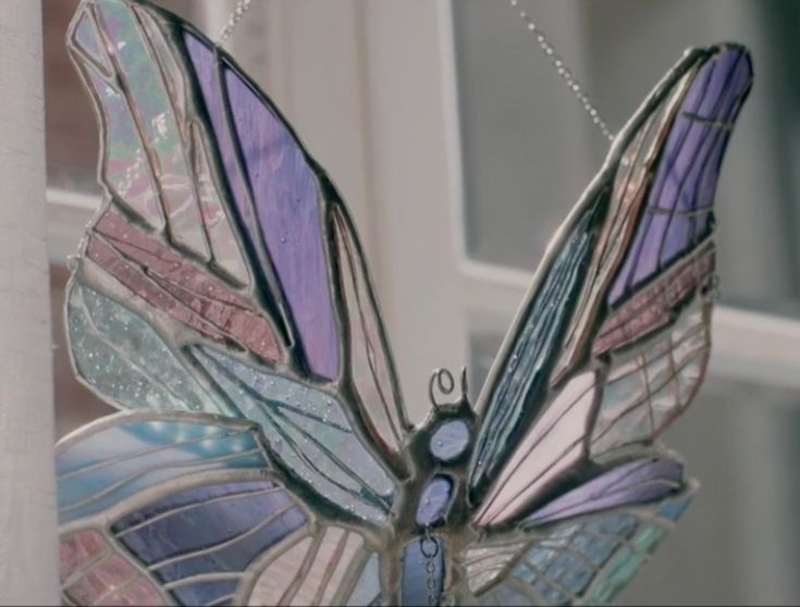 a stained glass butterfly hanging from a window