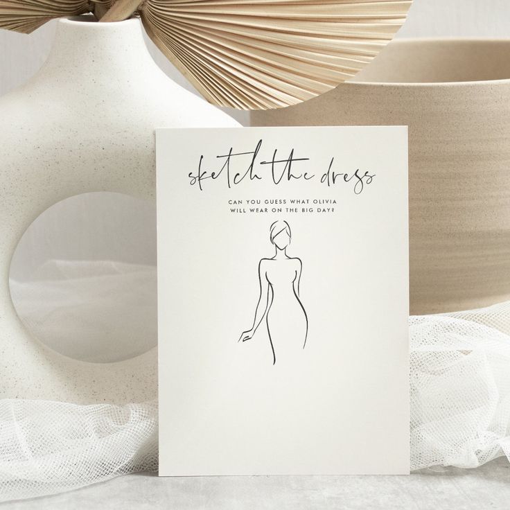 a white card with a drawing of a woman's body on it next to some vases