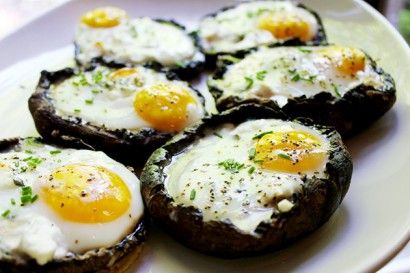 two fried eggs are on top of an eggplant in a brown bowl with green leaves