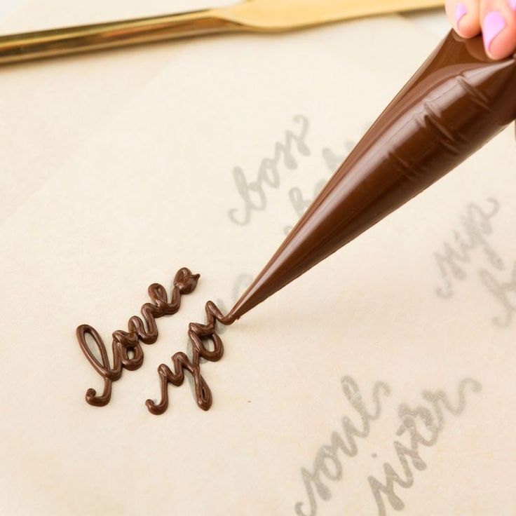 someone is writing the word love on a piece of paper with chocolate crayons