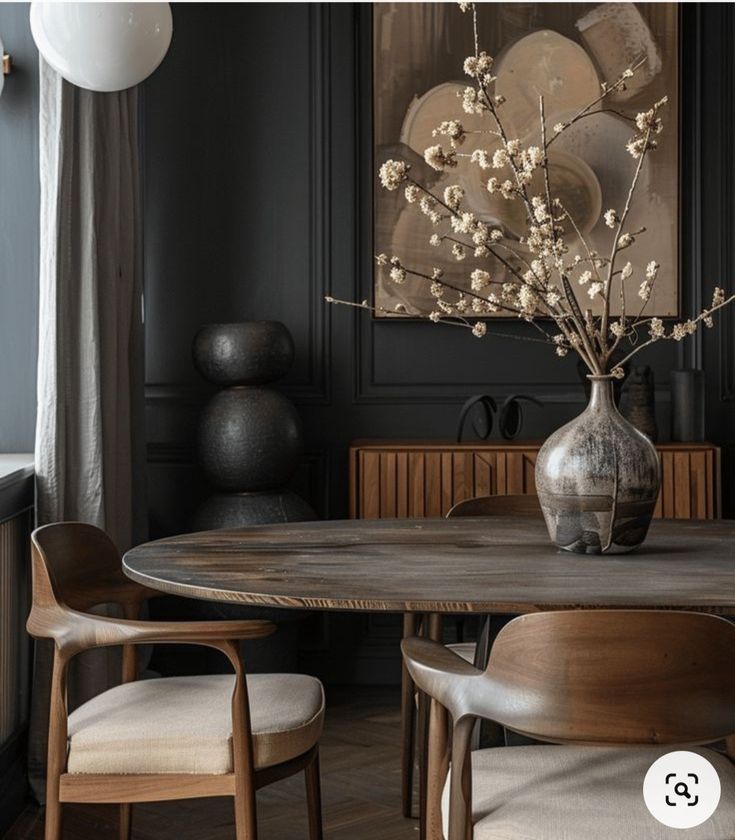 a dining room table with chairs and a vase filled with flowers on top of it