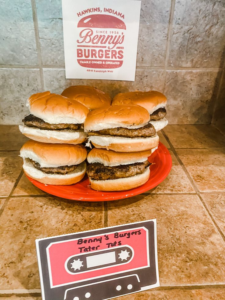 four hamburgers stacked on top of each other in front of a sign and tape recorder