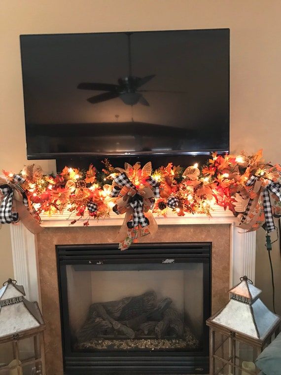 a fireplace decorated with fall leaves and lights